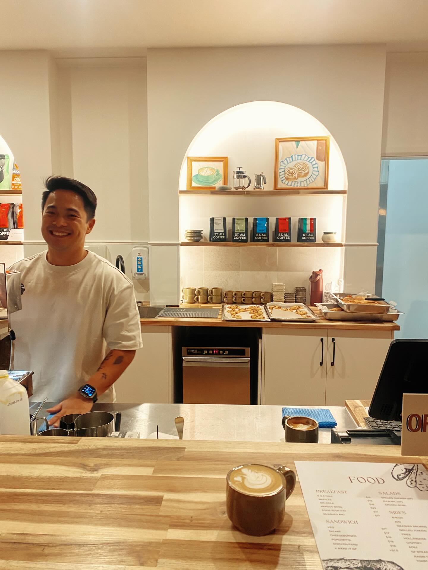 Barista smiling behind the counter with coffee on the bar
